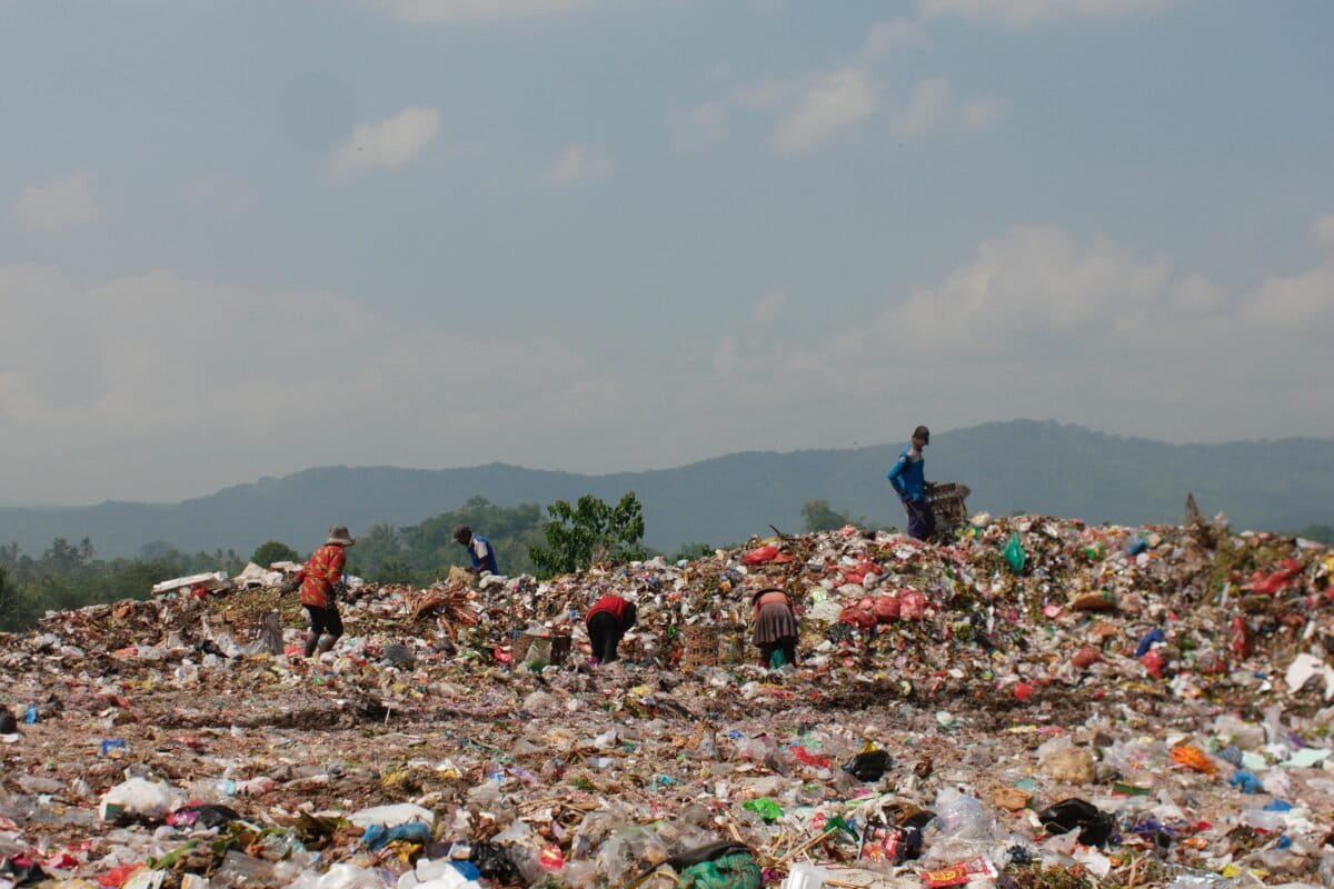 Young Indonesian volunteers from Wiskomunalian collecting waste along riverbank in East Java province