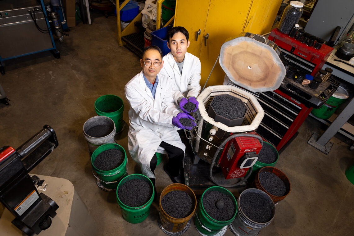 Scientists examining biochar pellets and woodchip filtration system at Illinois farm field test site