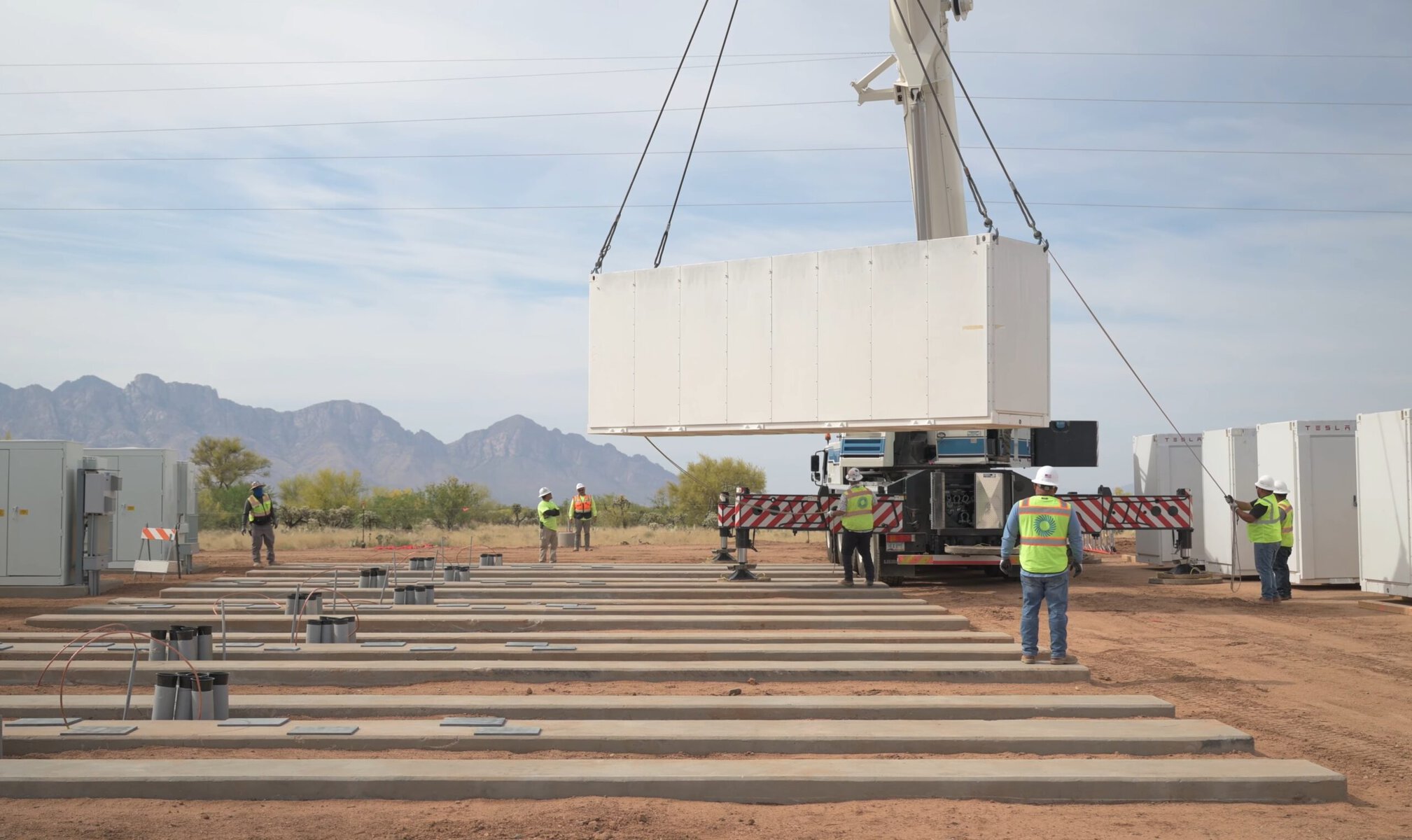 Large white battery storage containers lined up at California desert solar farm facility