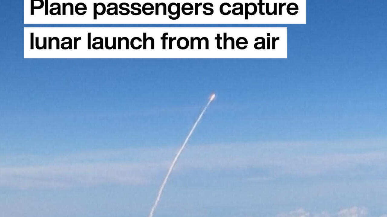 View from airplane window showing Artemis II rocket launching toward moon over Florida coastline