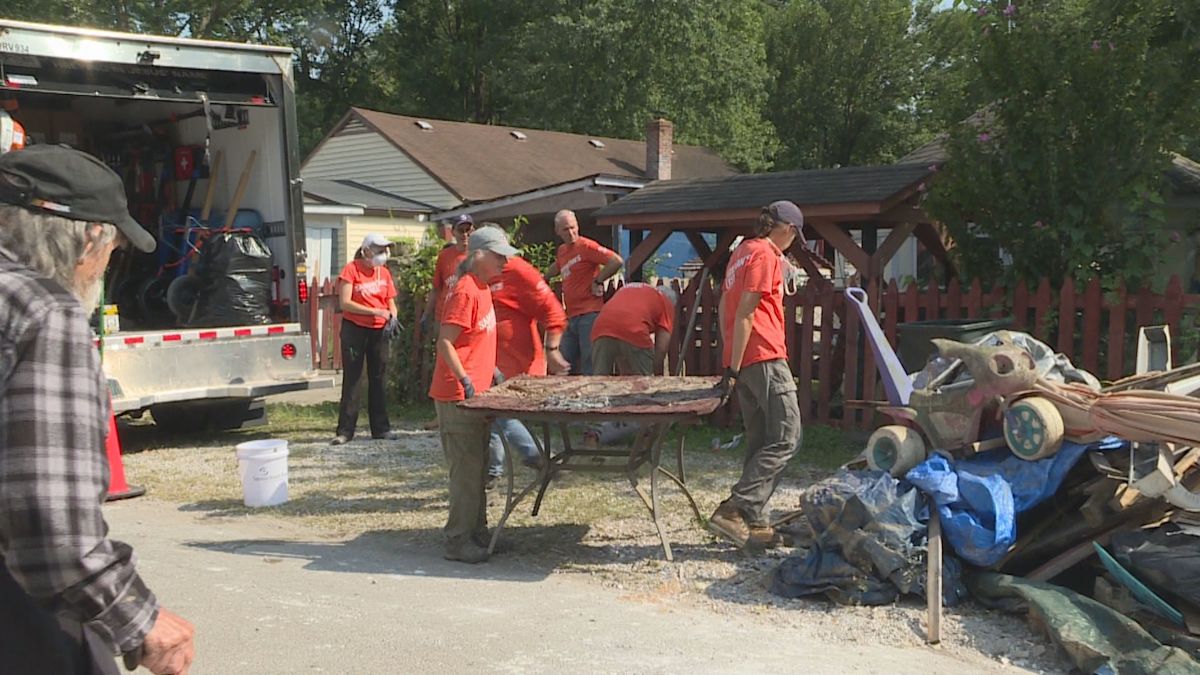 Volunteers working inside flood-damaged home removing walls and debris to help elderly homeowner rebuild