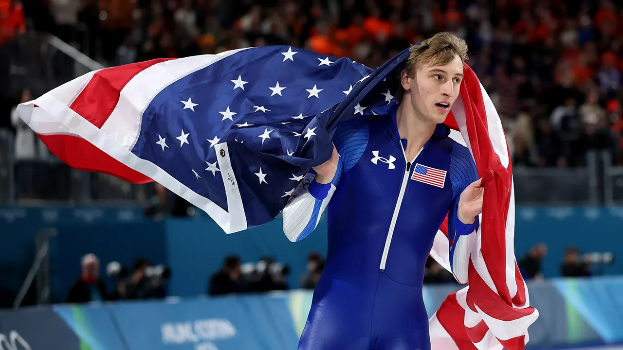 Jordan Stolz celebrates with arms raised after winning gold medal in speed skating