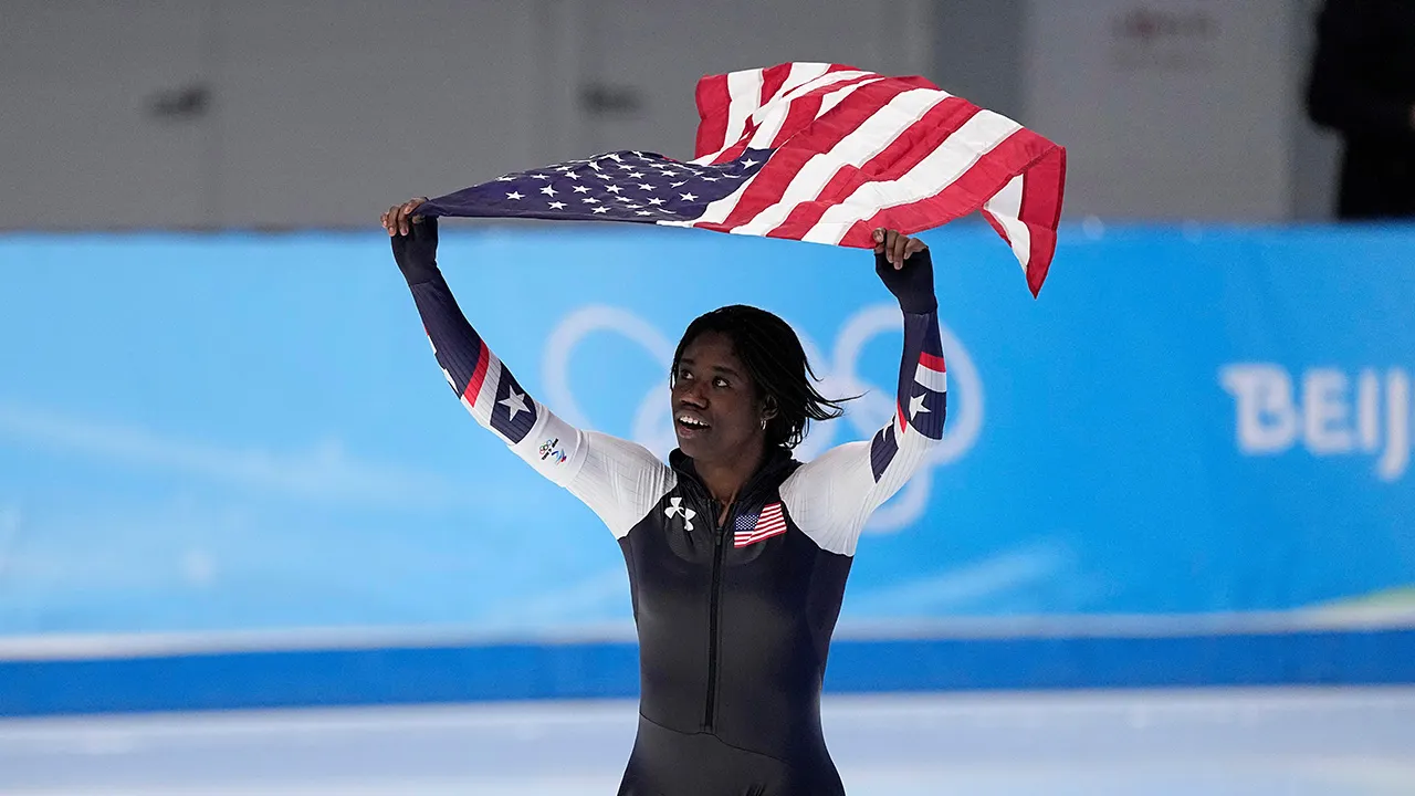Erin Jackson holds American flag after winning gold medal in speedskating at 2022 Winter Olympics