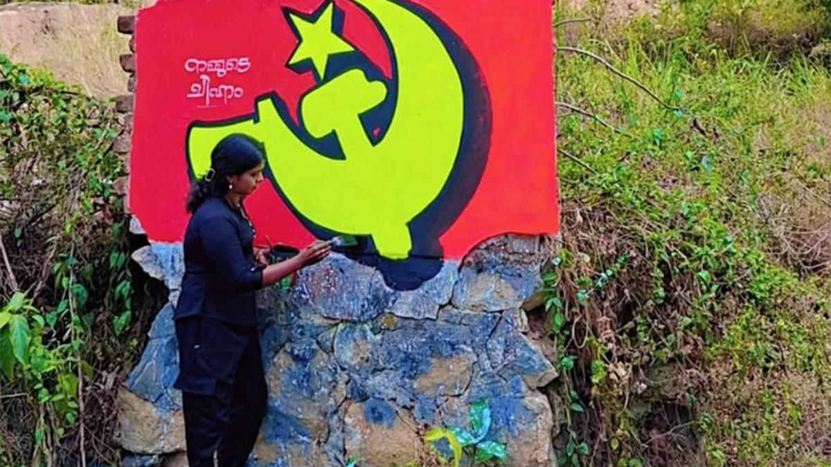 Woman artist painting colorful election graffiti on wall in Kerala India