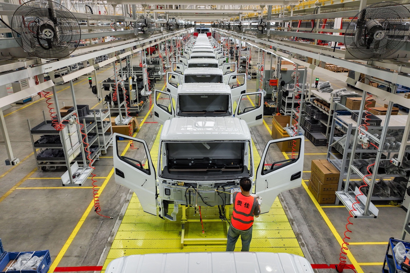 ** Workers assembling new energy vehicles on manufacturing line in modern Chinese factory