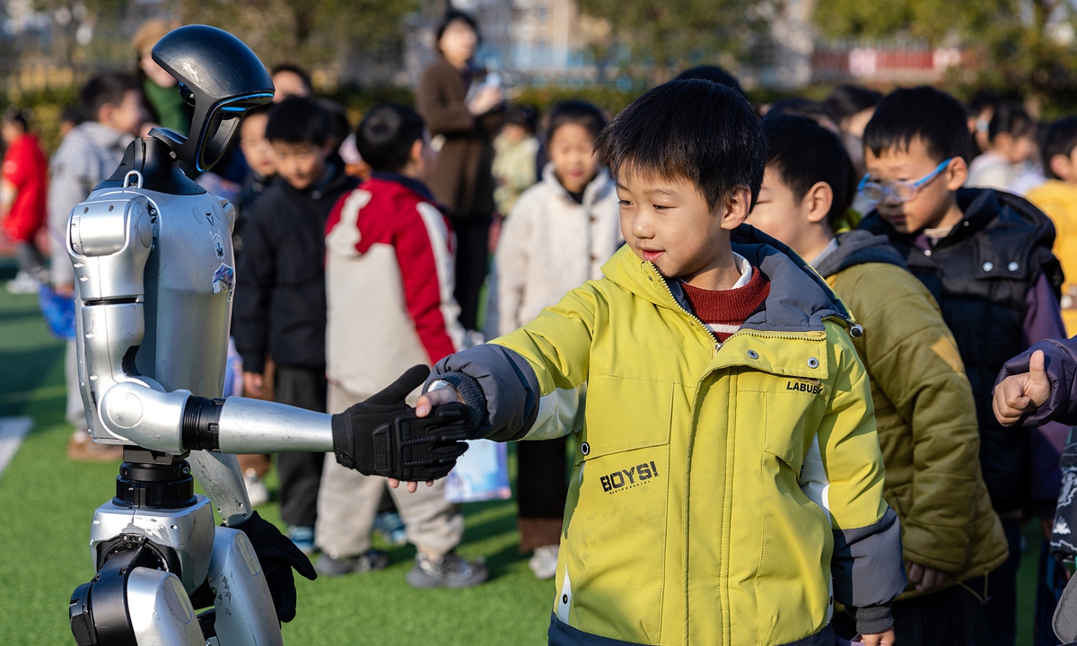 Young student in Huzhou China shaking hands with humanoid robot during innovative practical skills examination