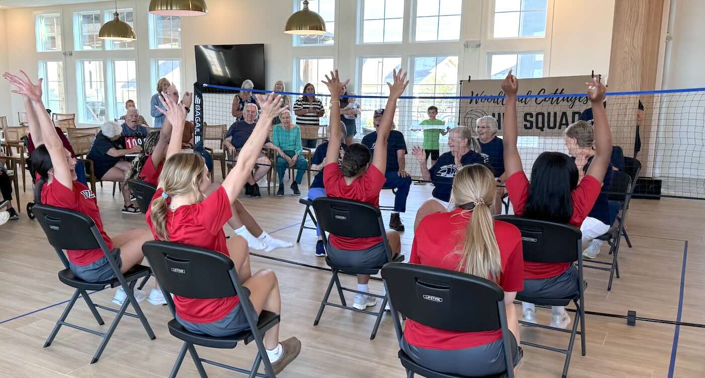 High school volleyball players and senior residents smiling together after chair volleyball game