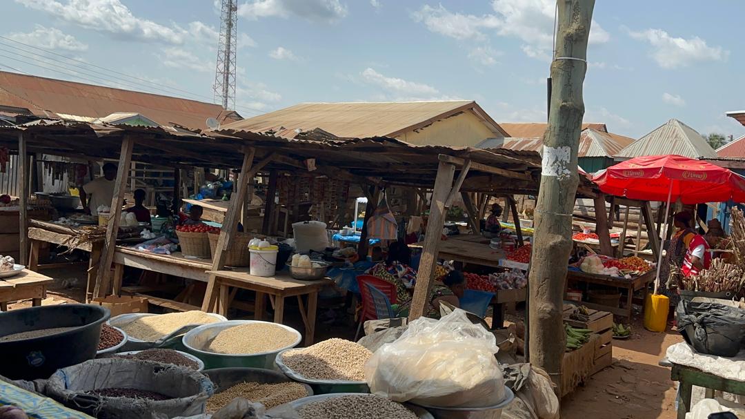 Crowded traditional market in Ghana with vendors under worn wooden structures and roofing