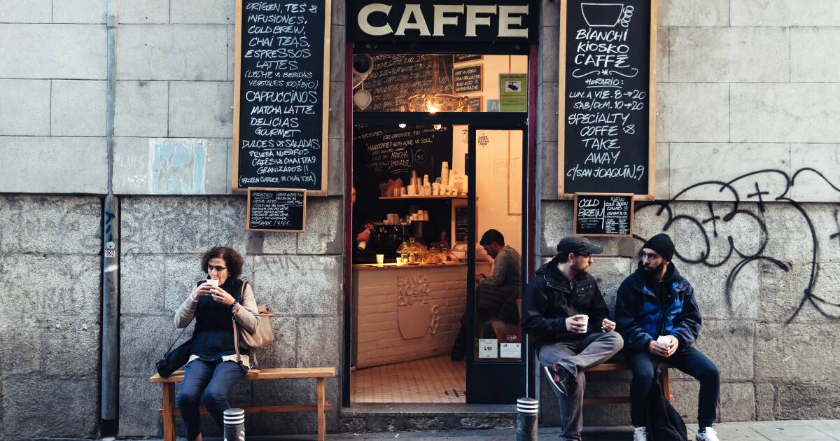 ** Young people walking through a vibrant Spanish city street showing economic growth and cultural diversity