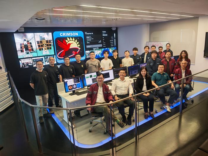 Research team members standing before CRIMSON-1 satellite displaying experimental solar panels and computing equipment