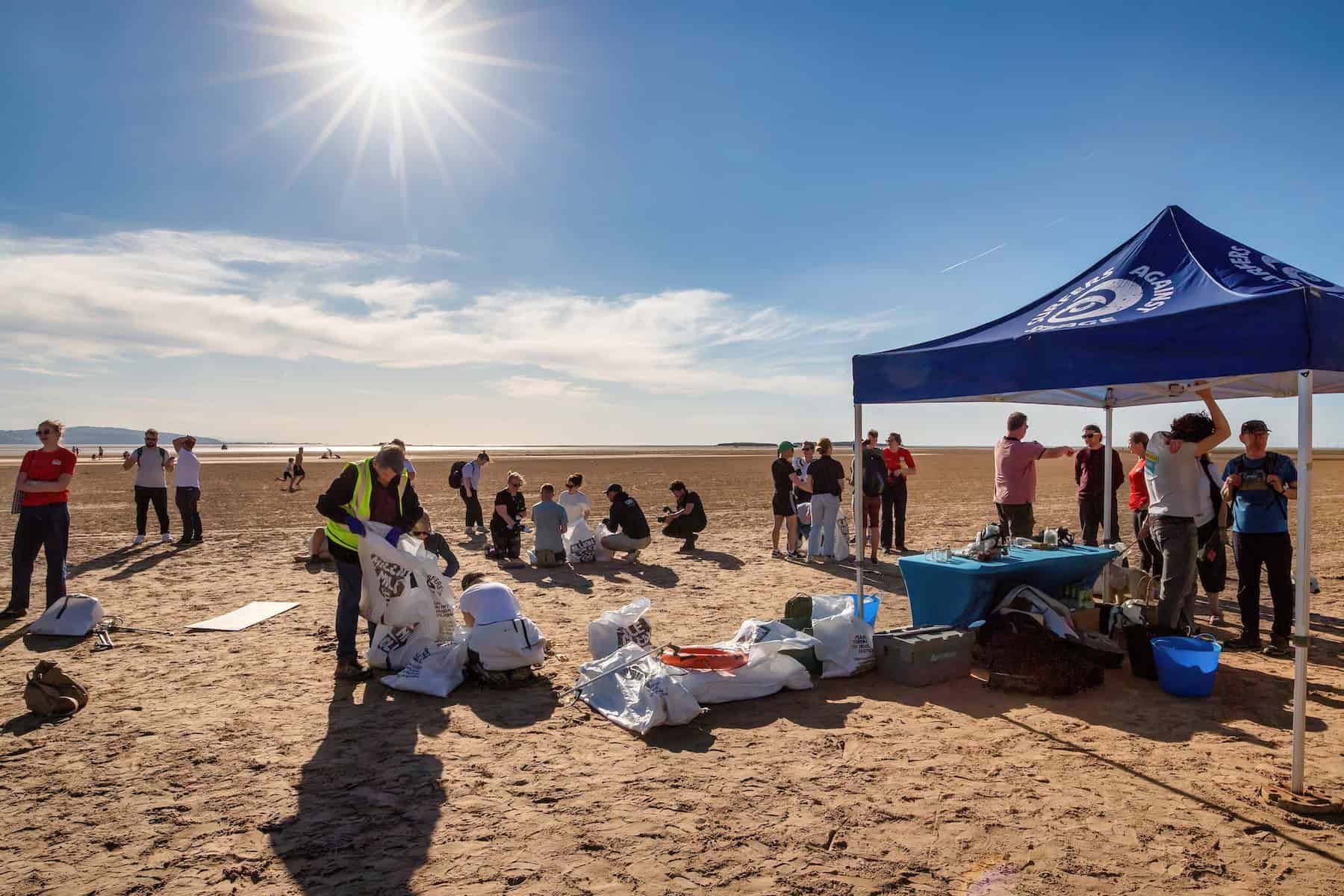Volunteers collecting plastic waste and debris from beach during Commonwealth Games cleanup campaign