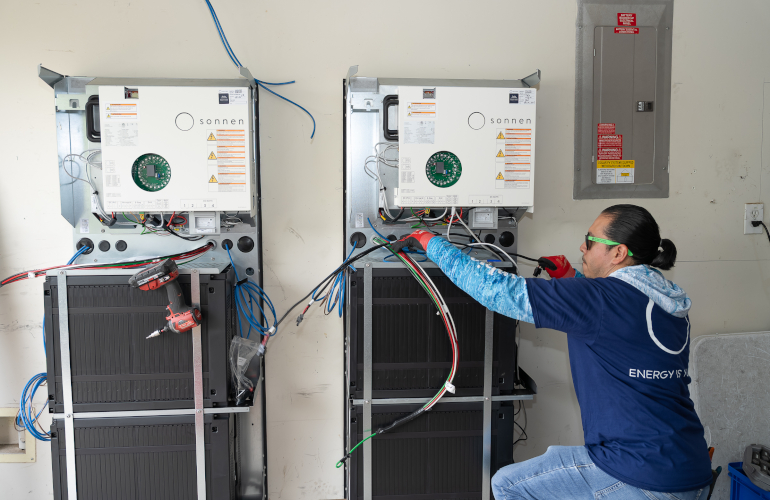 Solar panels installed on residential rooftops with battery storage units in Massachusetts neighborhood