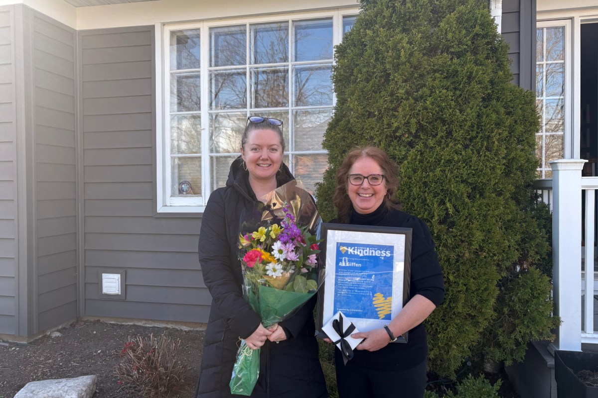 Woman smiling while holding bouquet of flowers and spa gift card at home